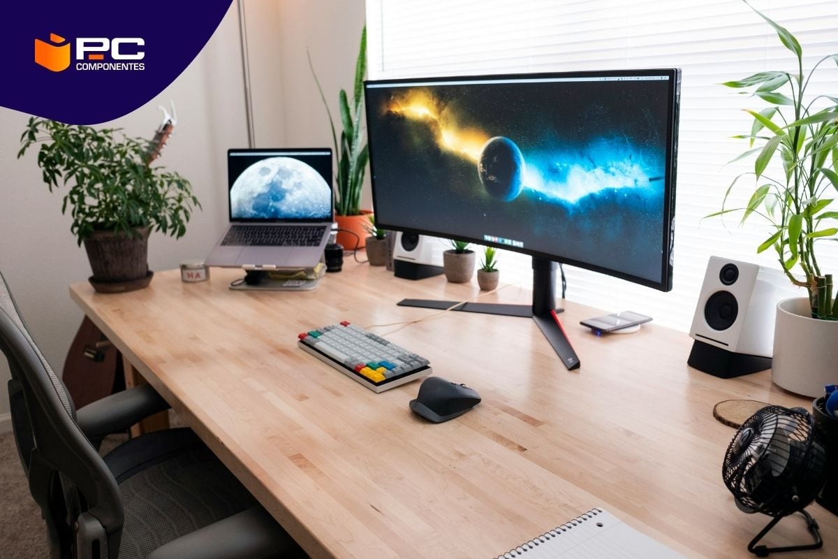 Guía para saber todo sobre la relación de aspecto en los monitores de PC Un escritorio de madera con un set up de trabajo: ordenador portátil, monitor, teclado y ratón