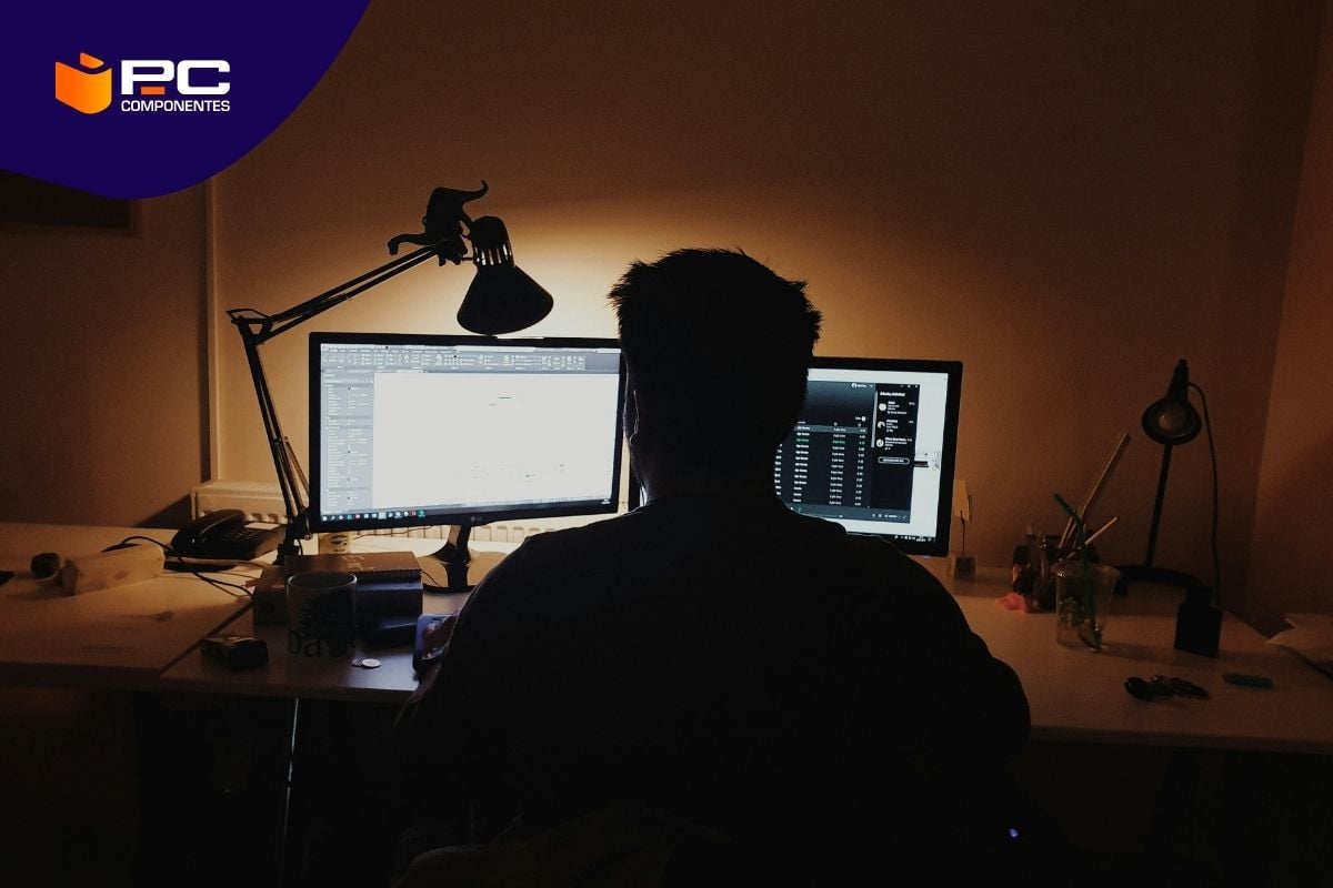 Un chico trabaja en su escritorio con dos monitores de PC